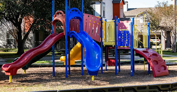 A playground with a blue and red slide and a green roofed structure.