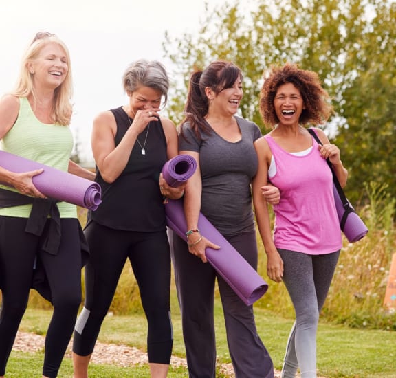 a group of women walking in a park holding yoga mats