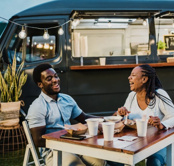a couple sitting at a table in front of a food truck