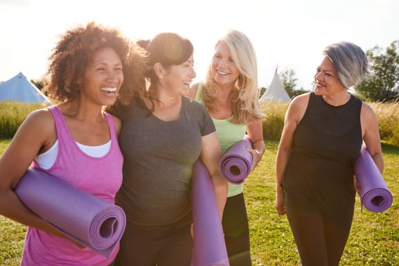 a group of women standing in a field holding yoga mats at River Stone Ranch, Austin, TX, 78749