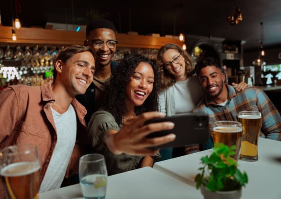 a group of people sitting at a table in a bar looking at a cell phone