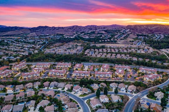an aerial view of a neighborhood of homes and mountains at sunset at Capriana at Chino Hills, Chino Hills, CA