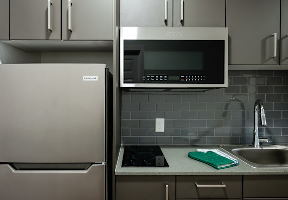 A kitchen with a refrigerator, microwave, and sink.