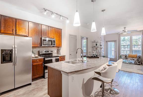 a kitchen with a island and a stainless steel refrigerator at Discovery at Craig Ranch, McKinney, TX