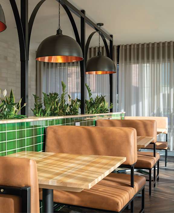 a wooden table in a restaurant with chairs and a plant