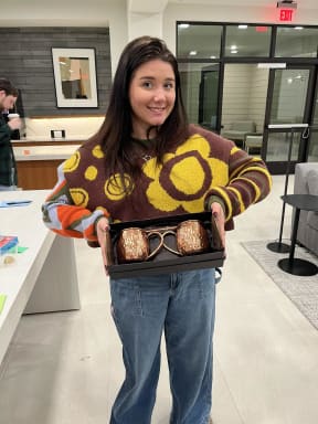 a woman holding a box of muffins