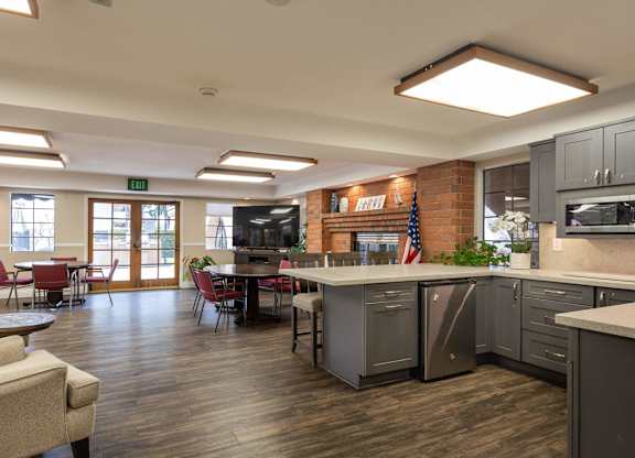 a clubhouse with a kitchen and a living room with a table and chairs at Huntington Terrace North Senior, California, 92648