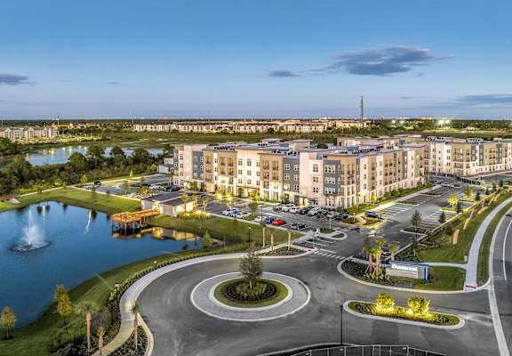 an aerial view of an apartment complex with a parking lot and a lake at The Overlook in Winter Garden, FL