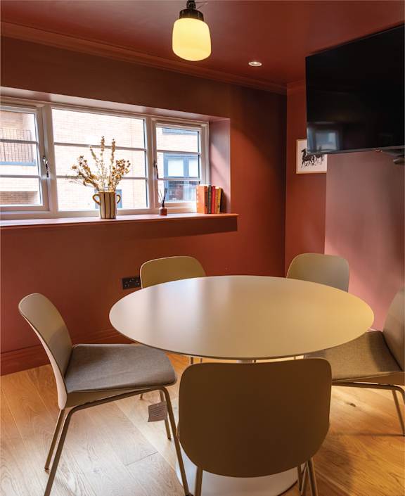 a wooden table in a restaurant with chairs and a plant
