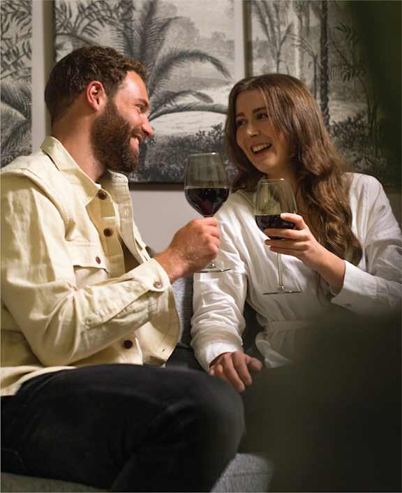 a man and a woman sitting on a couch with a glass of wine