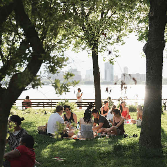 A group of people are sitting on the grass in a park.