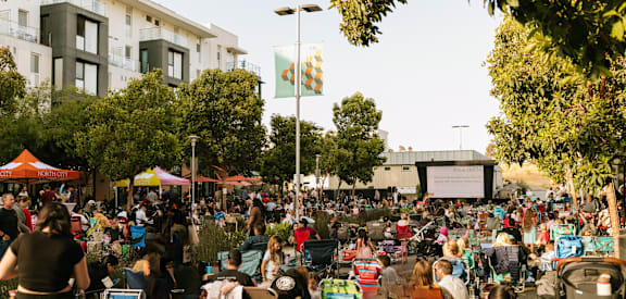 A large crowd of people are gathered in a park for an outdoor event.