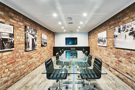 a conference room with a glass table and chairs and a television on the wall at The Meadows Apartments, Culver City , CA 90230
