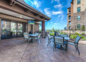 Thumbnail 11 of 78 - a patio with tables and chairs and a flat screen tv  at EdgeWater at City Center, Lenexa, KS