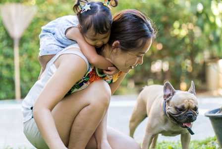 A woman and a child are playing with a dog in a park.