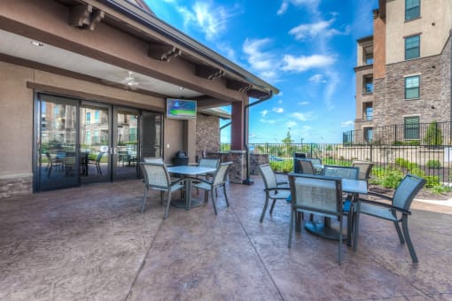 a patio with tables and chairs and a flat screen tv  at EdgeWater at City Center, Lenexa, KS