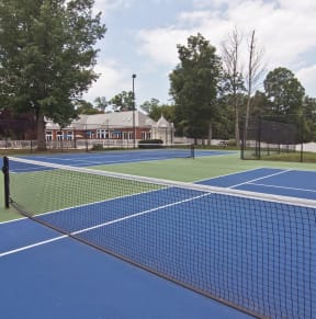 two tennis courts with a building in the background