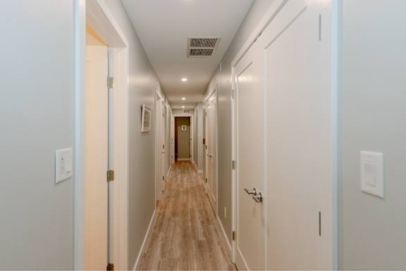 A long hallway with doors on both sides and a light on the wall.