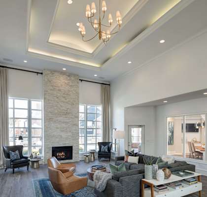 A modern living room with a stone fireplace and a chandelier.
