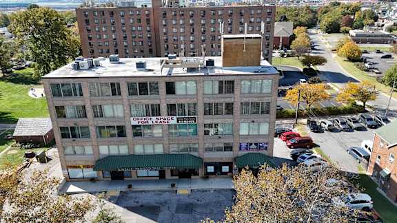 A large building with a sign that says "Office Space for Lease" is surrounded by a parking lot.