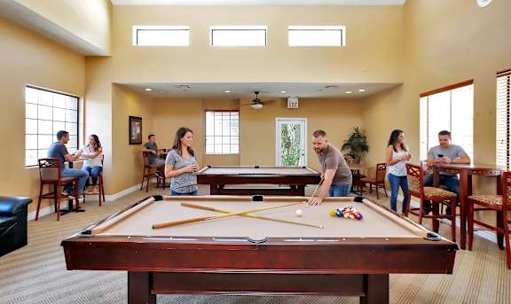 A group of people playing pool in a room.