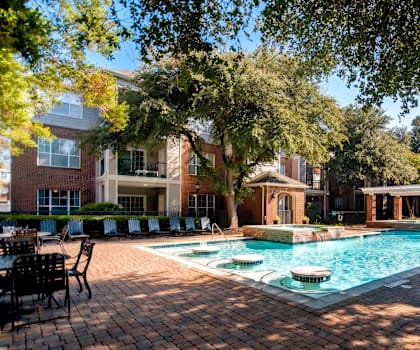 A pool surrounded by trees and chairs.