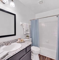 A bathroom with a white sink, toilet, and a mirror above the sink.