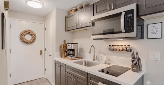 A kitchen with a white counter top and a white sink.