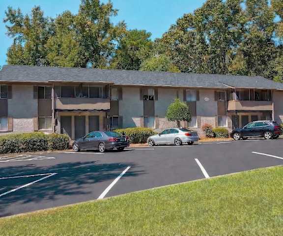 A parking lot in front of a building with cars parked.