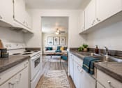 Thumbnail 1 of 8 - A kitchen with white cabinets and a rug on the floor.