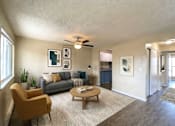 Thumbnail 6 of 8 - A living room with a yellow chair, grey couch, and a ceiling fan.