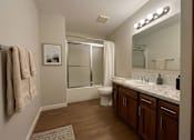 Thumbnail 2 of 8 - A bathroom with a toilet, sink, mirror, and a glass shower door.