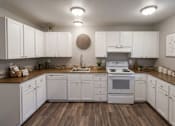 Thumbnail 4 of 8 - A kitchen with white cabinets and a wooden floor.