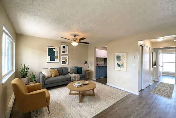 A living room with a yellow chair, grey couch, and a ceiling fan.