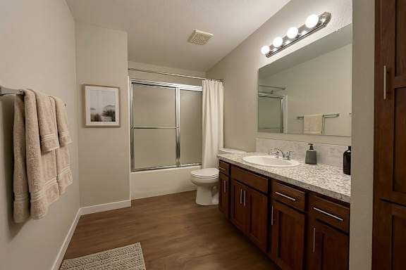 A bathroom with a toilet, sink, mirror, and a glass shower door.