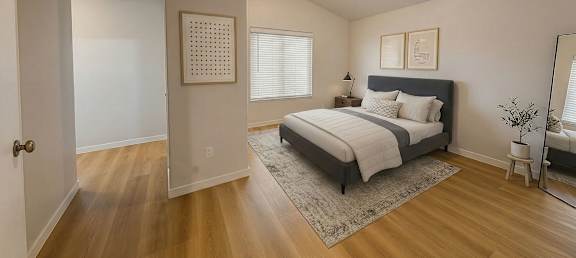 A bedroom with a bed, nightstand, and a plant.