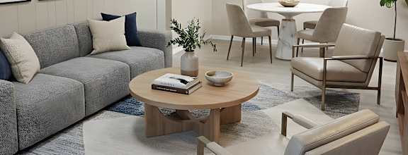 A grey couch with a wooden coffee table in front of it.