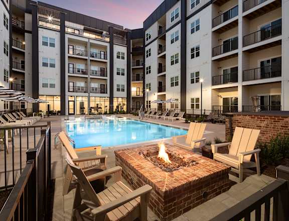 A fire pit sits in the middle of a patio surrounded by chairs.