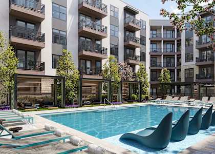 A swimming pool with lounge chairs in front of apartment buildings.