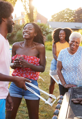 a group of people standing around a barbecue grill