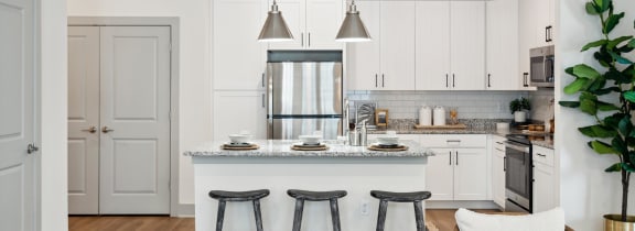 a kitchen with white cabinets and a marble counter top