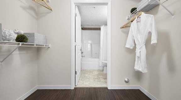 A white robe is hanging on a rack in a white bathroom.