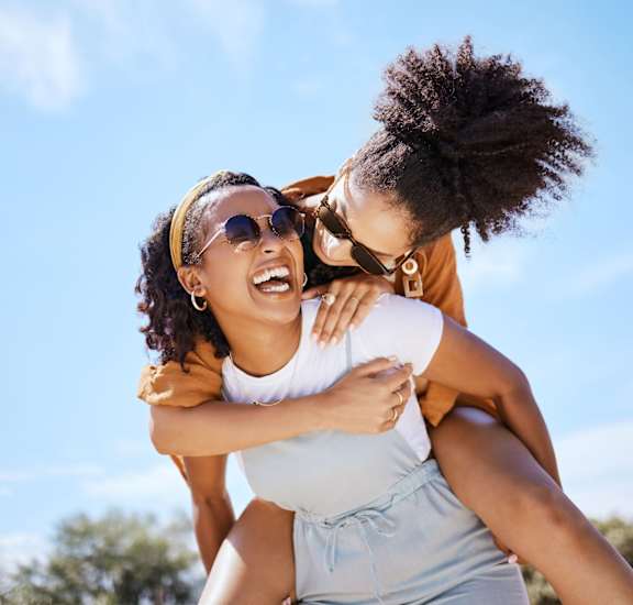 two women wearing sunglasses are laughing and having fun on a sunny day