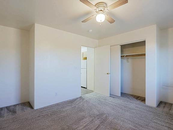 A room with a ceiling fan and carpeted floor.