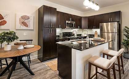 spacious kitchen with stainless steel appliances and a breakfast bar with a wooden table and chairs at Arlo Luxury homes Apartments, Little Rock, Arkansas
