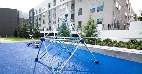 A blue playground structure in front of apartment buildings.