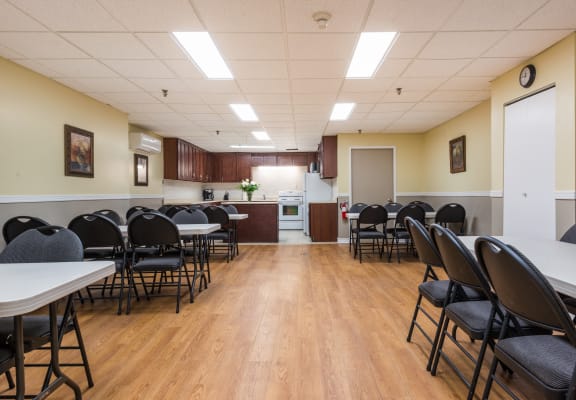 a multipurpose room with tables and chairs and a kitchen
