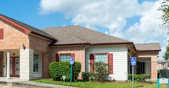 A brick house with a red roof and a sign on the front.