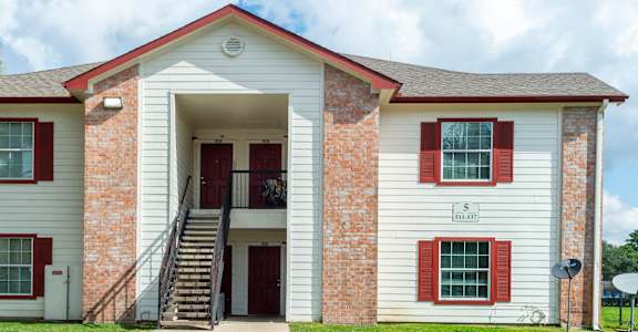 A white house with red shutters and a red door.