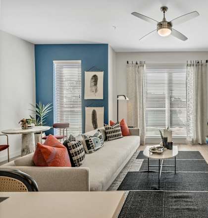 A living room with a beige couch, a coffee table, and a ceiling fan.